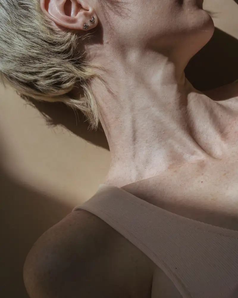 The side of a woman's neck and jaw in low afternoon sun, skin texture visible